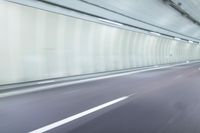 a blurry photo of a highway in an empty tunnel, with light coming through the opening