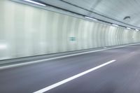 a blurry photo of a highway in an empty tunnel, with light coming through the opening