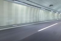 a blurry photo of a highway in an empty tunnel, with light coming through the opening