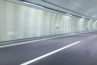 a blurry photo of a highway in an empty tunnel, with light coming through the opening