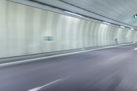 a blurry photo of a highway in an empty tunnel, with light coming through the opening