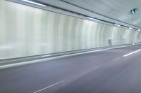 a blurry photo of a highway in an empty tunnel, with light coming through the opening