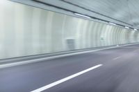 a blurry photo of a highway in an empty tunnel, with light coming through the opening