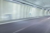 a blurry photo of a highway in an empty tunnel, with light coming through the opening