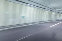 a blurry photo of a highway in an empty tunnel, with light coming through the opening