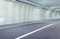 a blurry photo of a highway in an empty tunnel, with light coming through the opening