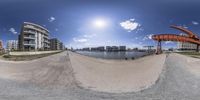 the skate park and the beach under a clear blue sky with clouds in it with a fisheye lens