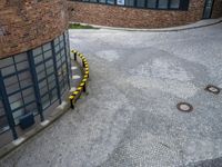 an aerial view of a brick building with yellow post markers lining the street that goes up from the outside