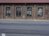 a stop sign on the side of an empty street by a brick building with windows