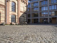 bikes parked in the middle of an empty street, in front of a building with brick walls