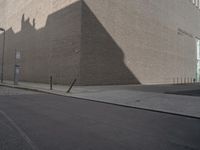 a shadow of a building on a city street and street signs on the sidewalk on both sides