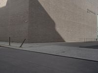 a shadow of a building on a city street and street signs on the sidewalk on both sides