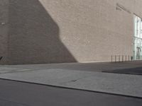 a shadow of a building on a city street and street signs on the sidewalk on both sides