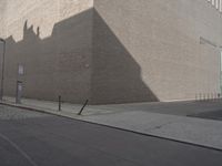 a shadow of a building on a city street and street signs on the sidewalk on both sides