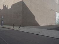 a shadow of a building on a city street and street signs on the sidewalk on both sides