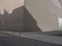 a shadow of a building on a city street and street signs on the sidewalk on both sides