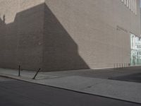 a shadow of a building on a city street and street signs on the sidewalk on both sides