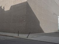 a shadow of a building on a city street and street signs on the sidewalk on both sides