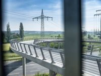 a long wooden bridge over a valley next to green grass and electricity poles are overhead