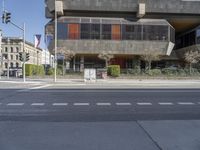 empty intersection in city with large concrete building behind it and traffic lights along side it