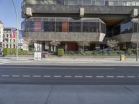 empty intersection in city with large concrete building behind it and traffic lights along side it