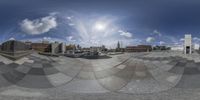 a fisheye lens of the plaza and cityscape with sun peeking through it