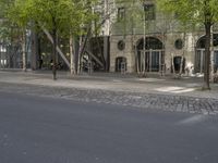 a city street lined with trees, benches and buildings on it's side,