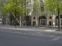 a city street lined with trees, benches and buildings on it's side,