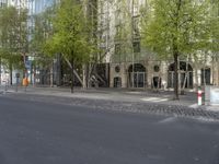 a city street lined with trees, benches and buildings on it's side,