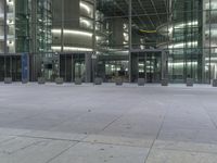 a large building with glass front doors on the ground and people walking around it and outside