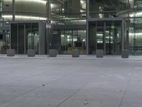 a large building with glass front doors on the ground and people walking around it and outside