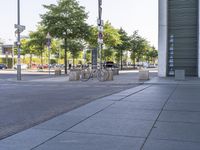 an empty bench is next to a sidewalk with trees in the background, in an urban area