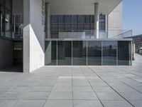 an empty courtyard next to an office building with glass walls in front of it's doors