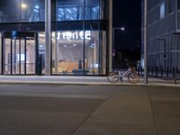 a orange bicycle parked next to a city building at night in front of an office