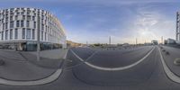 a fish - eye view shows a parking lot in the center of the city, with a large circular white building