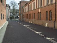 empty street next to a brick building and street sign with a bicycle on it, in front of the street