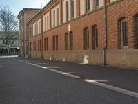 empty street next to a brick building and street sign with a bicycle on it, in front of the street