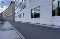 a empty street by a building with some glass on it's side windows and grass growing near the curb