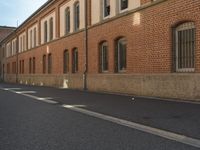 an empty city street with no traffic in front of buildings and brick walls in the city