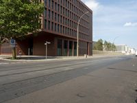 the building with three floors has many windows in it and cars on the street by the street