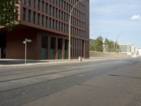 the building with three floors has many windows in it and cars on the street by the street