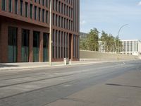 the building with three floors has many windows in it and cars on the street by the street