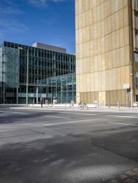 a city block is seen on an empty road with pedestrians walking around it and the sky is blue