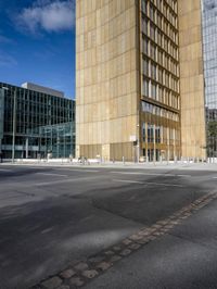 a city block is seen on an empty road with pedestrians walking around it and the sky is blue