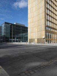 a city block is seen on an empty road with pedestrians walking around it and the sky is blue