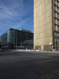 a city block is seen on an empty road with pedestrians walking around it and the sky is blue