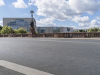 two street lights on a bridge over an empty street with buildings in the background,