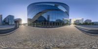 a shiny building reflecting on the exterior of it with multiple steps running through it and a round sidewalk