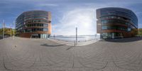 a circular panorama of two buildings in the city with water and trees in the background