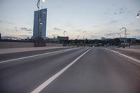 the street is empty with cars and lights on the side of it at night time